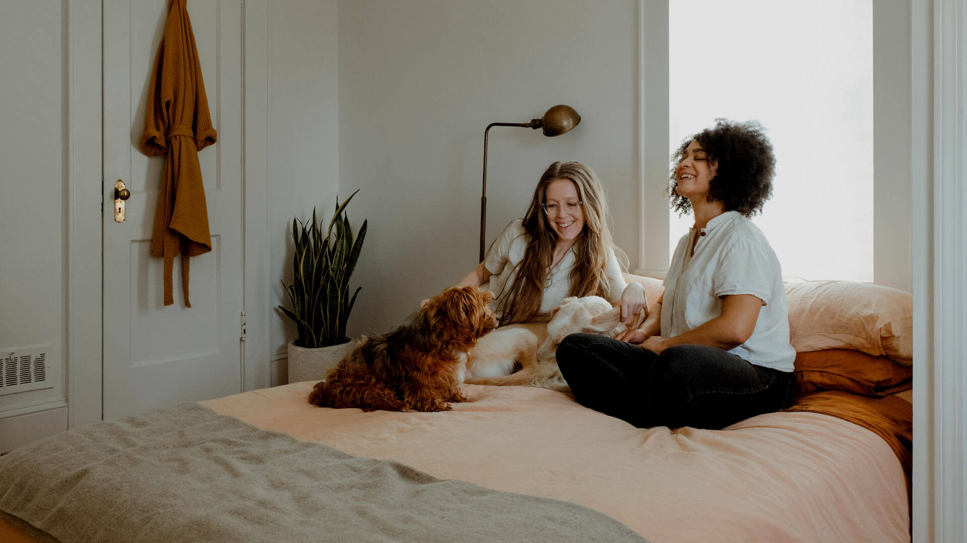 two women sitting on bed with dog